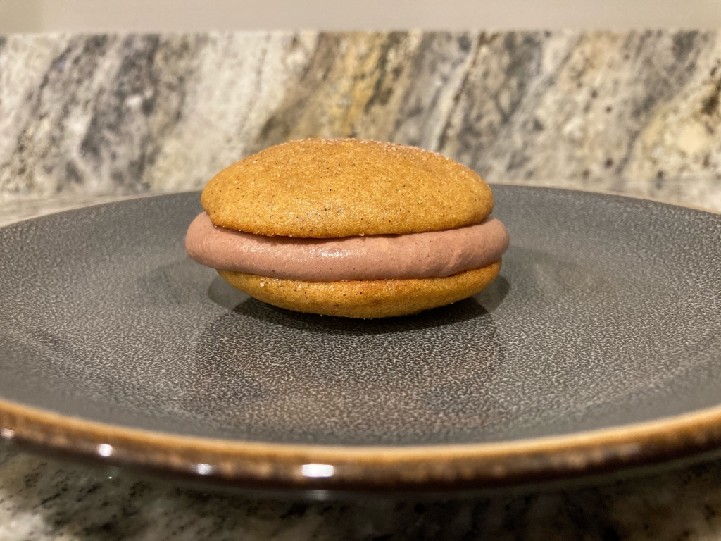 Pumpkin cookie sandwich with chocolate mousse in middle of cookies.